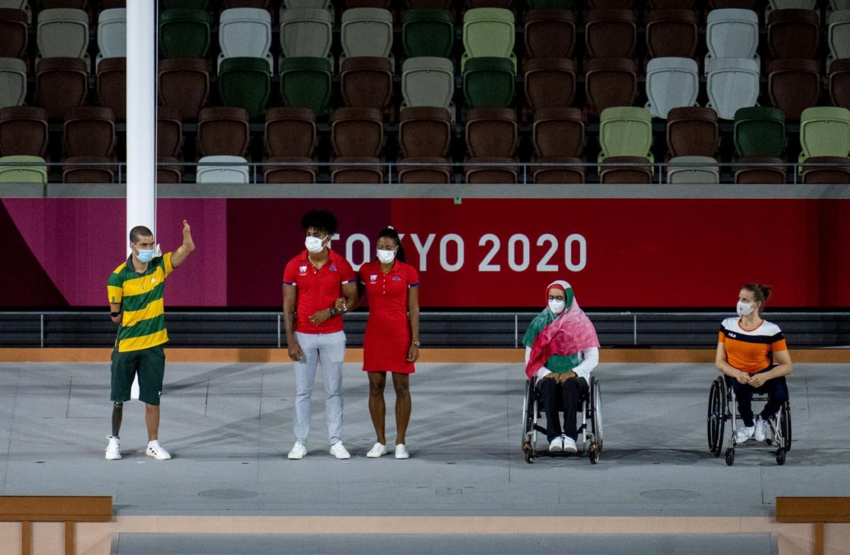 Four athletes and a guide wearing face masks are being presented. 